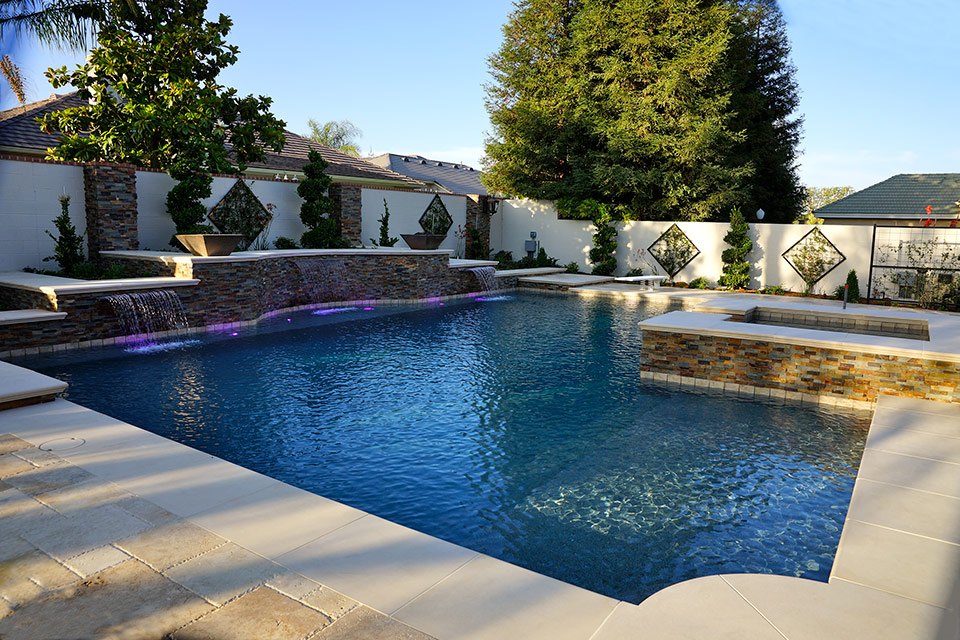 Custom pool and spa with water features, fire bowls, custom lighting and beautiful shrubs.