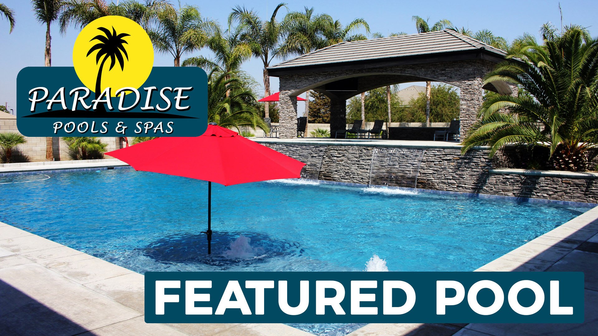 Massive, deep swimming pool with water features, spa and red umbrellas built by Paradise Pools & Spas.